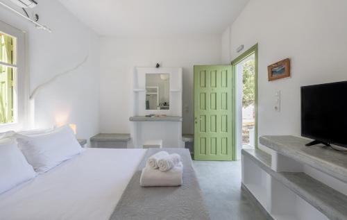 a white bedroom with a bed and a television at Pente Elies Milos in Pollonia