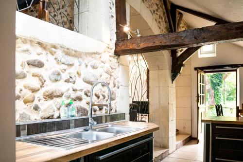 een keuken met een wastafel en een stenen muur bij Maison de charme à proximité de Pau - 3 chambres - 6 p - Jardin in Sendets