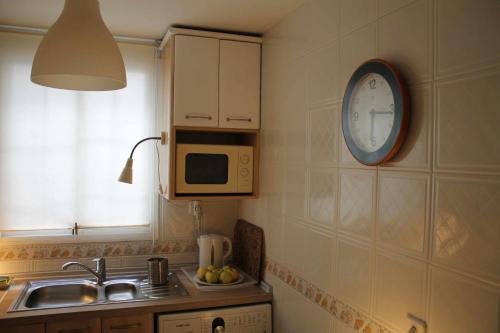 una cocina con fregadero y un reloj en la pared en Acogedor apartamento en el Rabal en Zaragoza