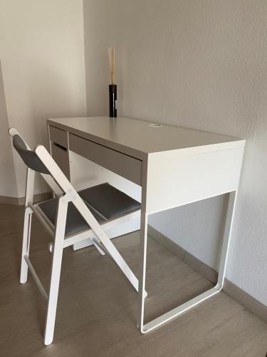 a white desk with a chair next to a wall at Exklusiv, modernes Apartment mit Balkon in Böblingen