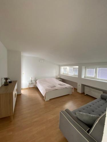 a white bedroom with a bed and a couch at Apartman S&D Rogoznica in Rogoznica