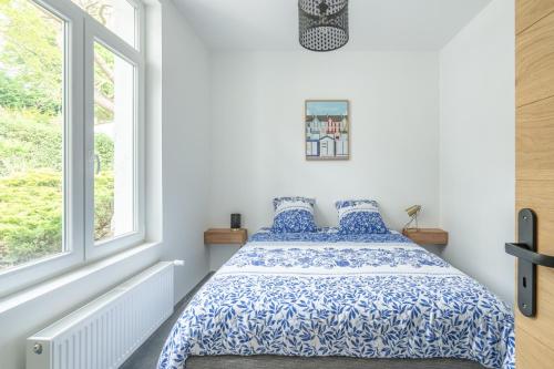 um quarto com uma cama com lençóis e janelas azuis e brancas em Lumière espace et convivialité à 2 pas de Wimereux em Wimille