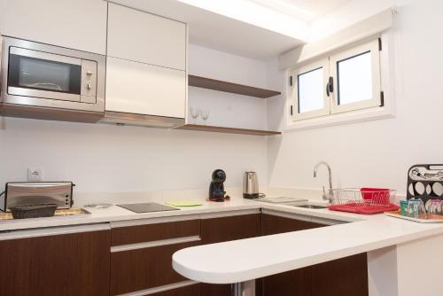 a kitchen with white cabinets and a white counter top at Quinta da Paz in Caniço