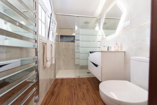 uma casa de banho branca com um WC e um chuveiro em Quinta da Paz no Caniço
