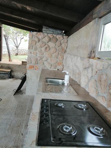 a stove top in a kitchen with a stone wall at Sobe Apartma Galic in Novi Vinodolski