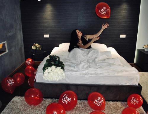 a woman laying on a bed in a room with red balloons at Club House Arkadia Beach in Odesa