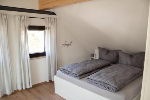 a white bedroom with a bed and a window at Ferienwohnung Kurz "Panoramablick" in Wertheim