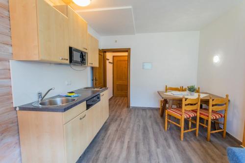 eine Küche mit einem Waschbecken und einem Tisch mit Stühlen in der Unterkunft Huberhof 2 by Alpenidyll Apartments in Schladming