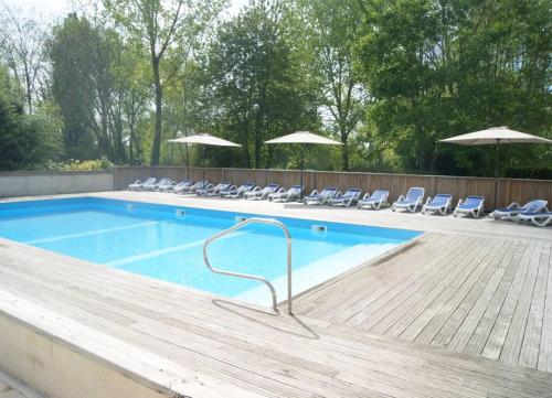 a large swimming pool with chairs and umbrellas at Camping des Tourbières - Gîtes in Vendoire