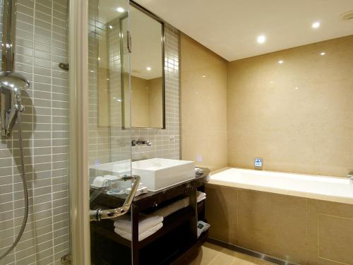 a bathroom with a sink and a bath tub at The Tango Hotel Taipei XinYi in Taipei