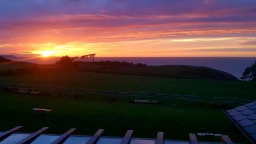 a sunset over a field with a fence and the ocean at Hotel Rural La Sobreisla in Puerto de Vega