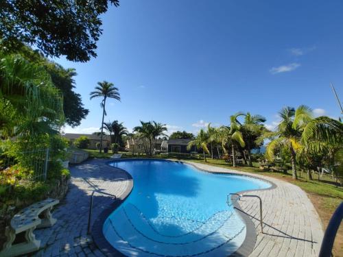 a swimming pool in a resort with palm trees at Cheerful 2 bedroom cottage with a communal pool in Hibberdene