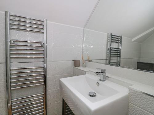 a white bathroom with a sink and a mirror at Forever Summer in Lymington