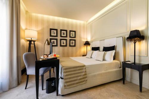 a hotel room with a bed and a desk and a bed at Profumo Collection Colosseo in Rome