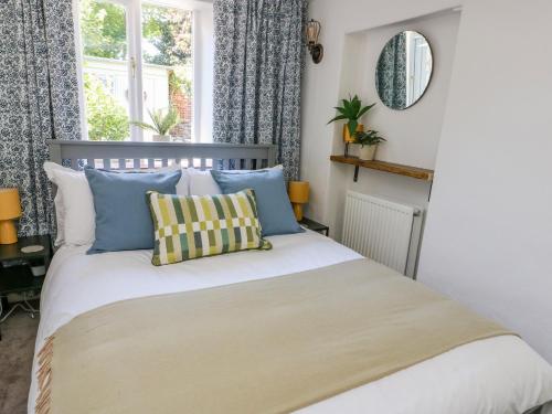 a bedroom with a bed with blue and yellow pillows at Crabapple Cottage in Llanfairfechan