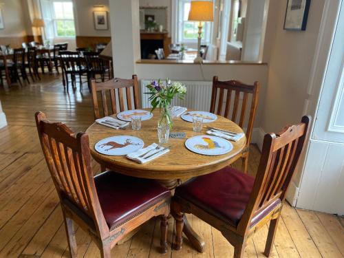 a wooden table with plates and flowers on top of it at The Gordon Arms Restaurant with Rooms in Yarrow
