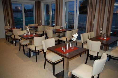 a restaurant with tables and white chairs and windows at CASILINO Hotel A 24 Wittenburg in Wittenburg