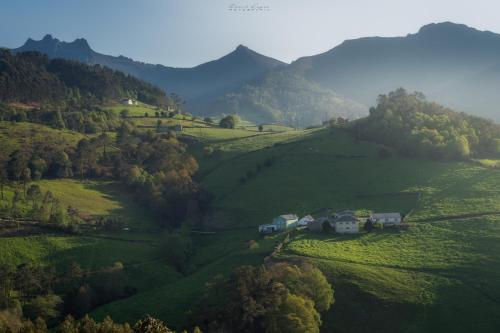 a house on a hill in a green valley at Hotel Rural La Sobreisla in Puerto de Vega