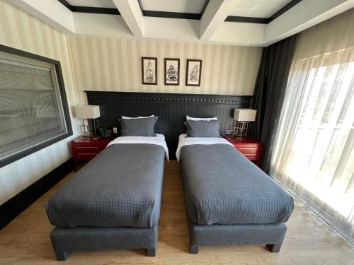 two beds in a room with two windows at Hotel Marina Bay Göcek in Göcek