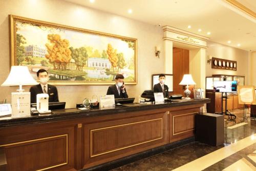 three men sitting at a counter in a hotel lobby at Fushin Hotel Taipei in Xizhi