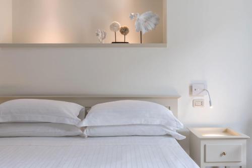 a white bed with white pillows and a night stand at Murè Hotel Numana in Numana