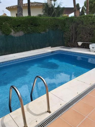 a swimming pool with two metal rails next to a house at La Palmera in Estepona