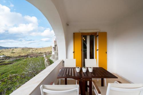 a balcony with a wooden table and white chairs at Pirgos Suites in Panormos