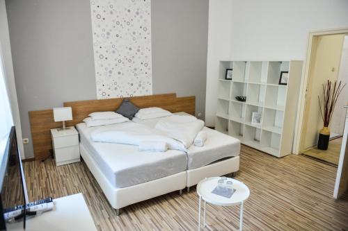a bedroom with a white bed and a table at Élmény Balaton Hotel in Alsóörs