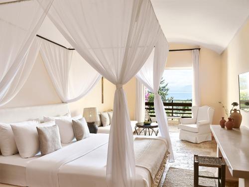 a bedroom with a large white bed with curtains at Grecotel LUXME Daphnila Bay in Dassia