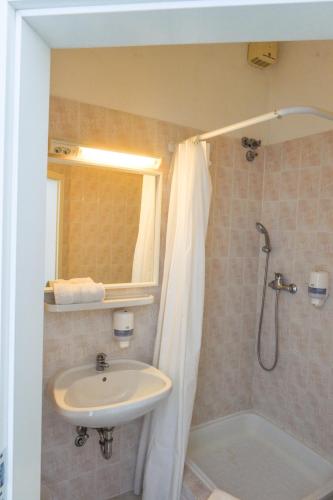 a bathroom with a sink and a shower at Élmény Balaton Hotel in Alsóörs