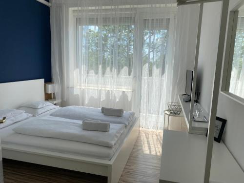 a bedroom with a bed and a large window at Élmény Balaton Hotel in Alsóörs