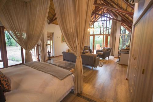 Kubu Metsi Lodge في Matlhagame: غرفة نوم مع سرير وغرفة معيشة