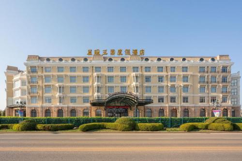 ein großes beigefarbenes Gebäude mit vielen Fenstern in der Unterkunft Discoveryland Hotel Dalian in Dalian