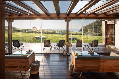 a screened in porch with two beds and a table and chairs at Hotel Rural La Sobreisla in Puerto de Vega