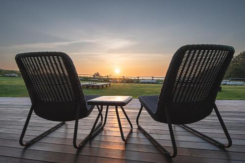 two chairs sitting on a deck watching the sunset at Hotel Rural La Sobreisla in Puerto de Vega