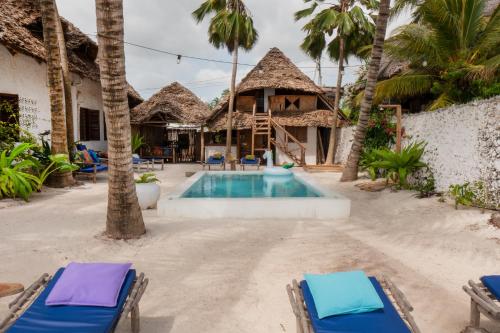 a resort with a pool and chairs and palm trees at Mamamapambo Boutique Hotel in Jambiani