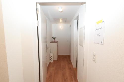 a hallway with white walls and wood floors and a white door at KoBi Apartments Falkenplatz in Luzern