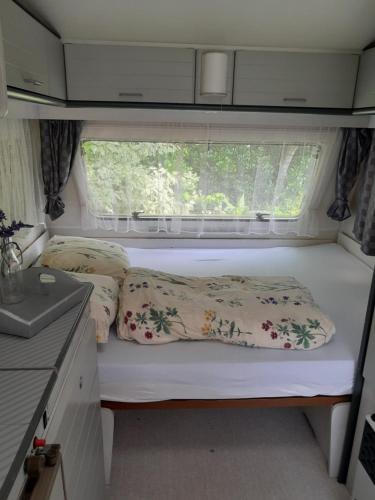 a bed in an rv with pillows and a window at Romala's Home Caravan in Kiel