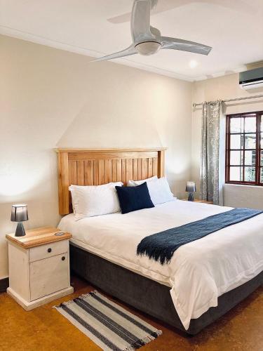 a bedroom with a large bed with a ceiling fan at Bergdale Cottages in Hazyview