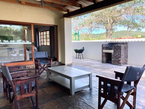 a patio with chairs and a table and a fireplace at Bergdale Cottages in Hazyview
