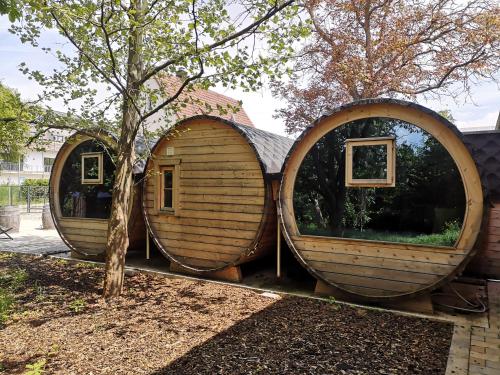 zwei große kreisförmige Holzhäuser neben einem Baum in der Unterkunft Übernachten im Weinfass in Volkach