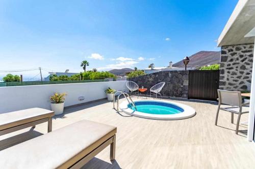 een patio met een zwembad en een tafel en stoelen bij Suites Bene LANZAROTE in La Asomada