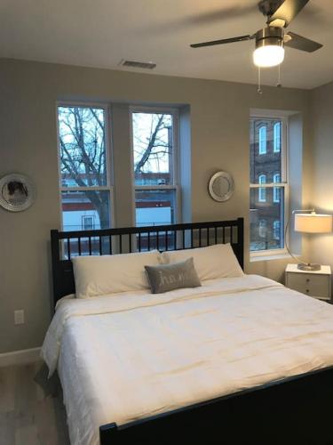 a bedroom with a large white bed with two windows at HOME AWAY HOME - Chic 2 BR Capitol Hill DC in Washington, D.C.