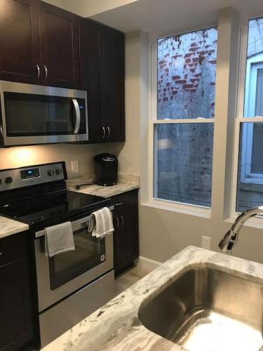 a kitchen with a sink and a stove and a microwave at HOME AWAY HOME - Chic 2 BR Capitol Hill DC in Washington, D.C.