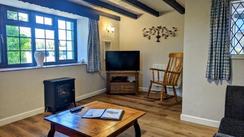 a living room with a fireplace and a tv at Yetland Farm Holiday Cottages in Combe Martin