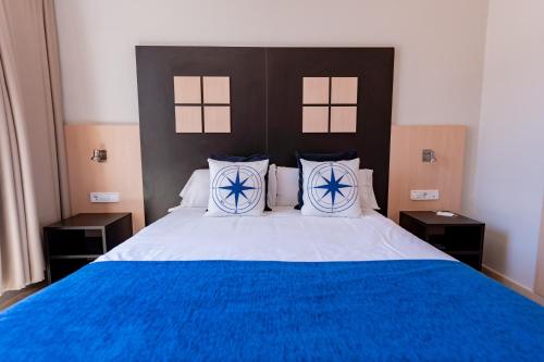 a bedroom with a large bed with blue sheets and pillows at Hotel Aubí in Sant Antoni de Calonge