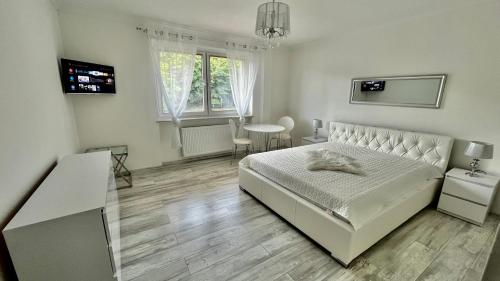 a white bedroom with a bed and a table at VILLA MARYNARZA in Ustka