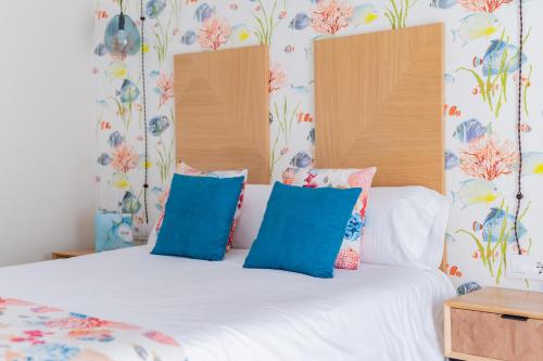 a bedroom with a white bed with blue pillows at Hotel Aubí in Sant Antoni de Calonge