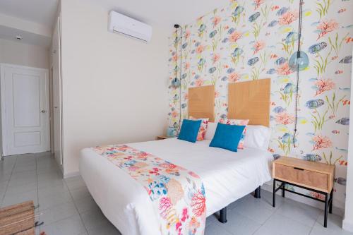 a bedroom with a large white bed with blue pillows at Hotel Aubí in Sant Antoni de Calonge