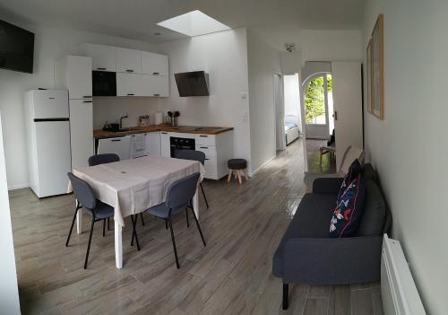 uma cozinha e sala de estar com uma mesa e um sofá em Charmant et lumineux logement, au cœur de Cabourg em Cabourg